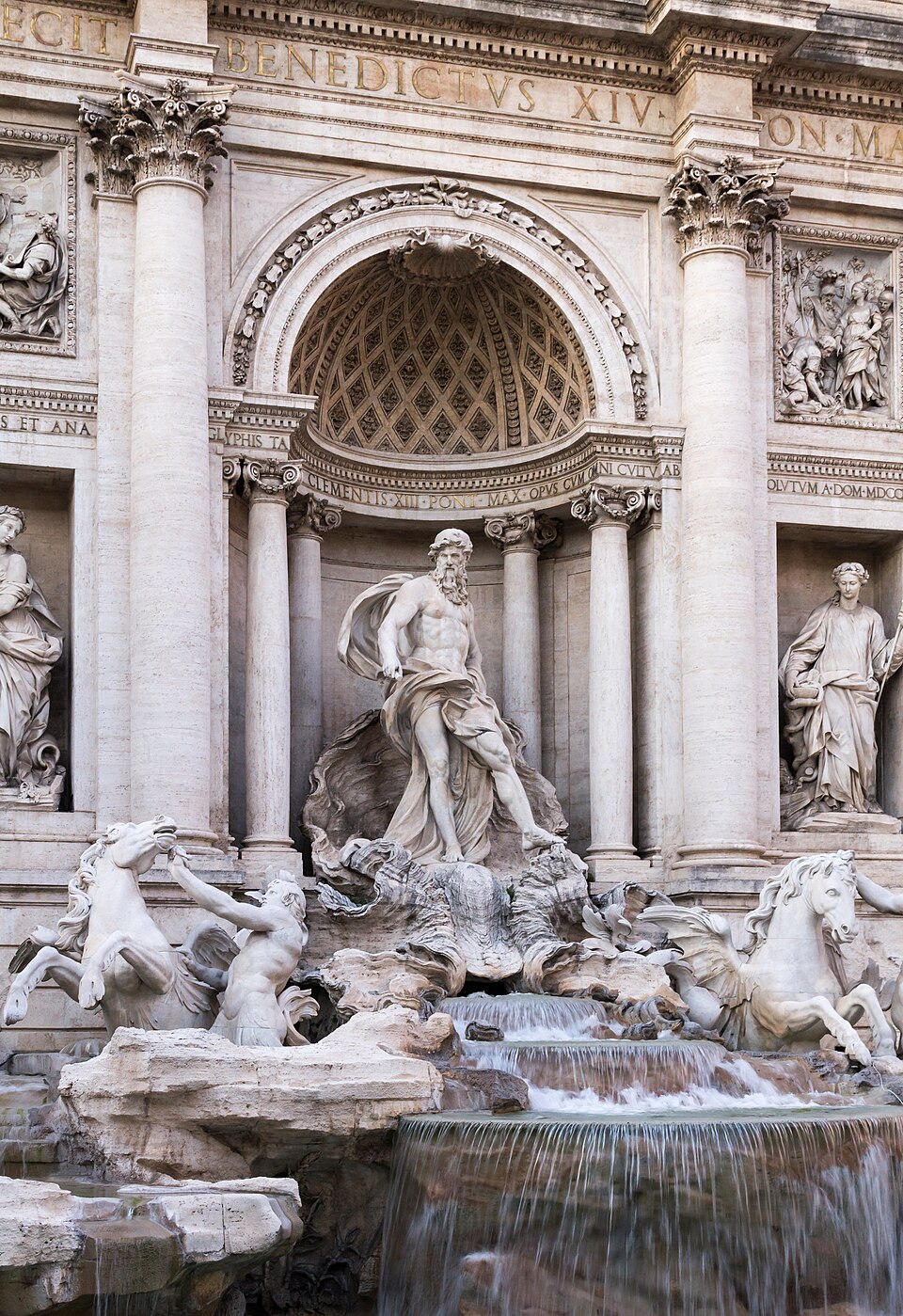 The Trevi Fountain in Rome illuminated at dusk with crowds gathered at its edge
