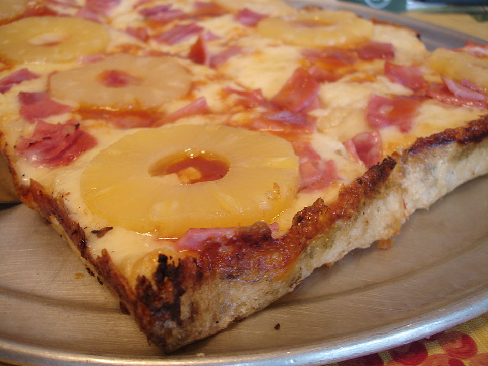 A Hawaiian pizza topped with pineapple chunks and ham