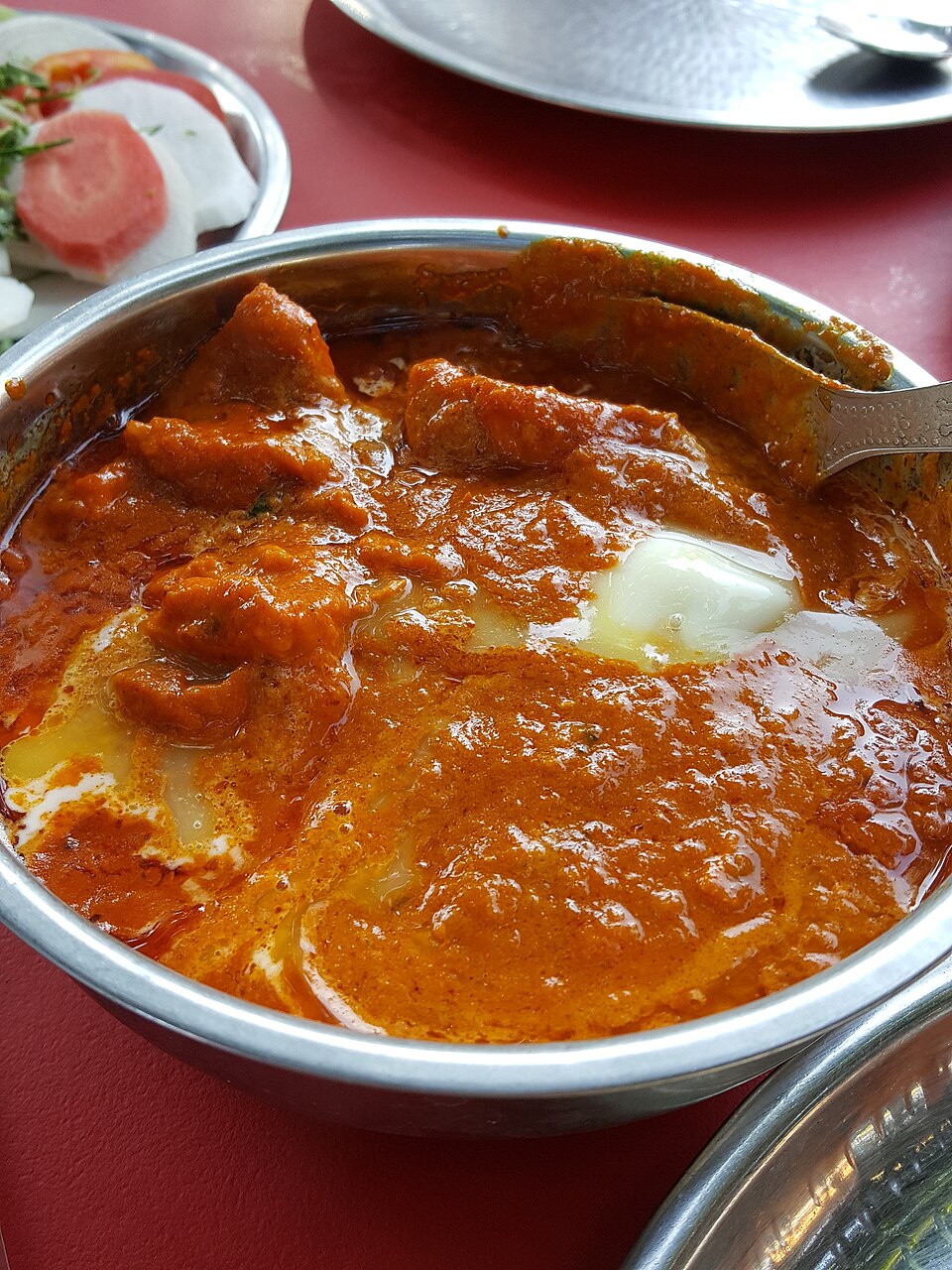 A bowl of chicken tikka masala in a creamy tomato sauce with rice