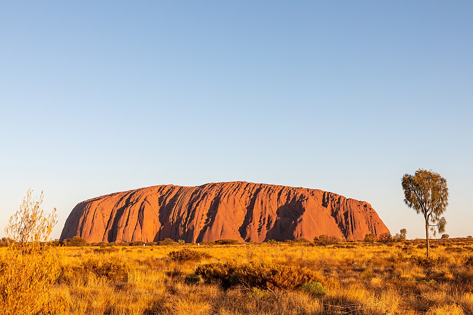 The sandstone monolith of Uluru glowing red at sunset in central Australia