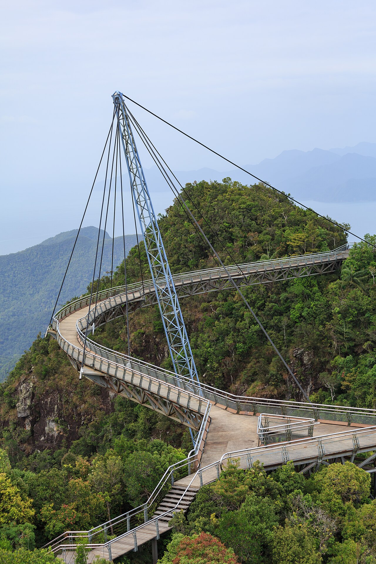 The curved Langkawi Sky Bridge suspended from a single pylon high above rainforest in Malaysia