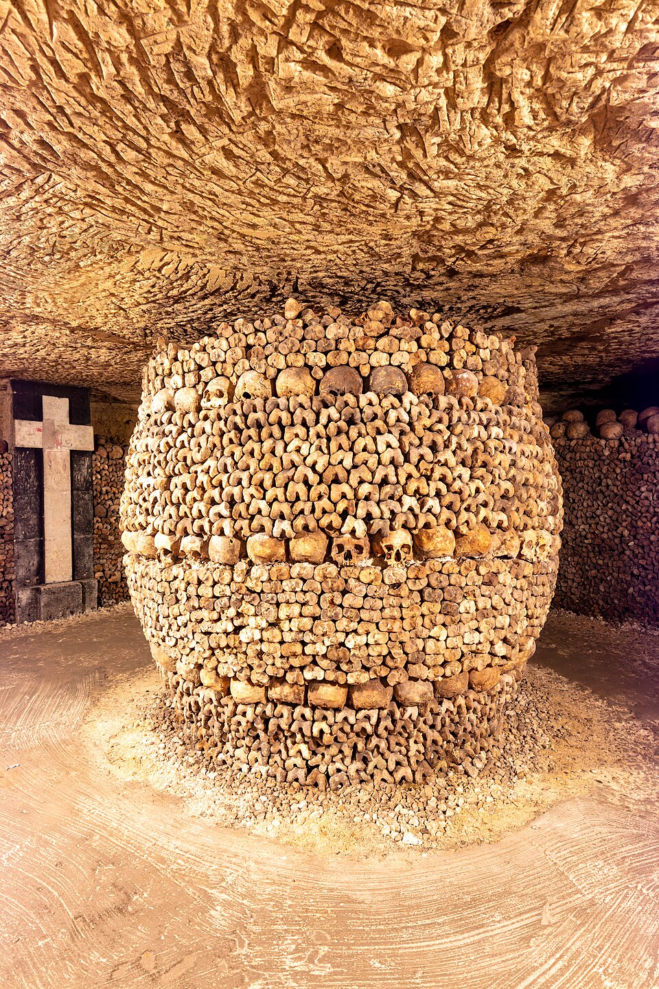 The Catacombs of Paris showing walls lined with human skulls and bones arranged in patterns underground