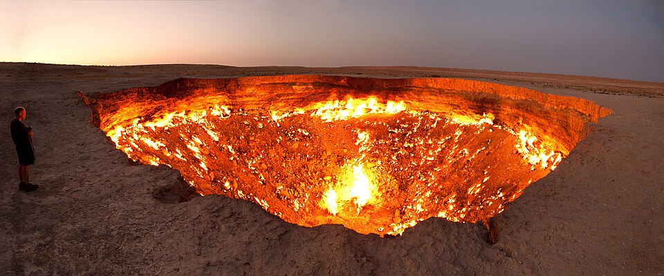 The Darvaza gas crater in Turkmenistan glowing with orange fire in the darkness of the desert at night