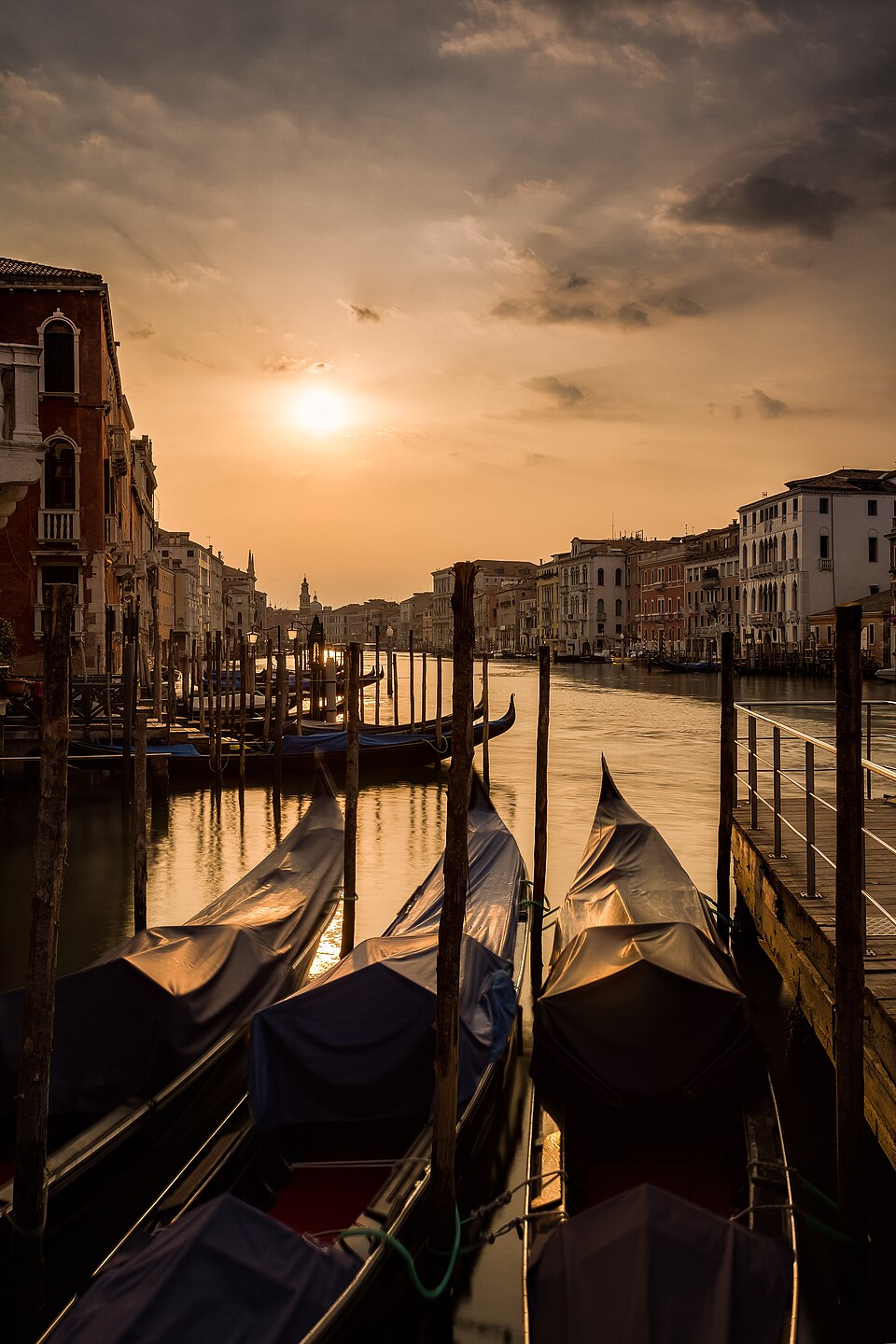 Early morning Venice canal with a gondola crossing under stone bridges before the day-tripper crowds arrive