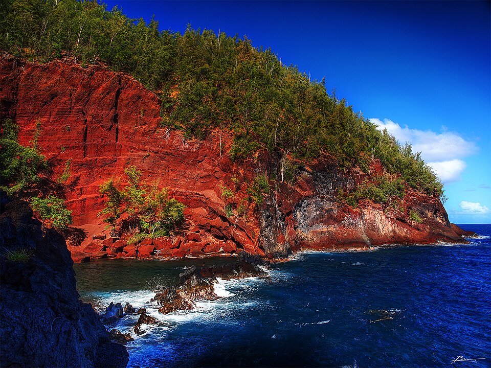 The rust-red eroding cinder cliff of Kauiki Head above Kaihalulu Bay near Hana on Maui, the source of the beach red sand