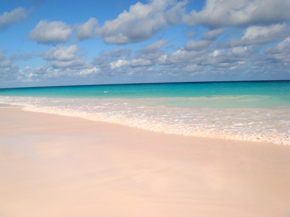 The soft pink sand and turquoise shallow water of Pink Sands Beach on Harbour Island in the Bahamas