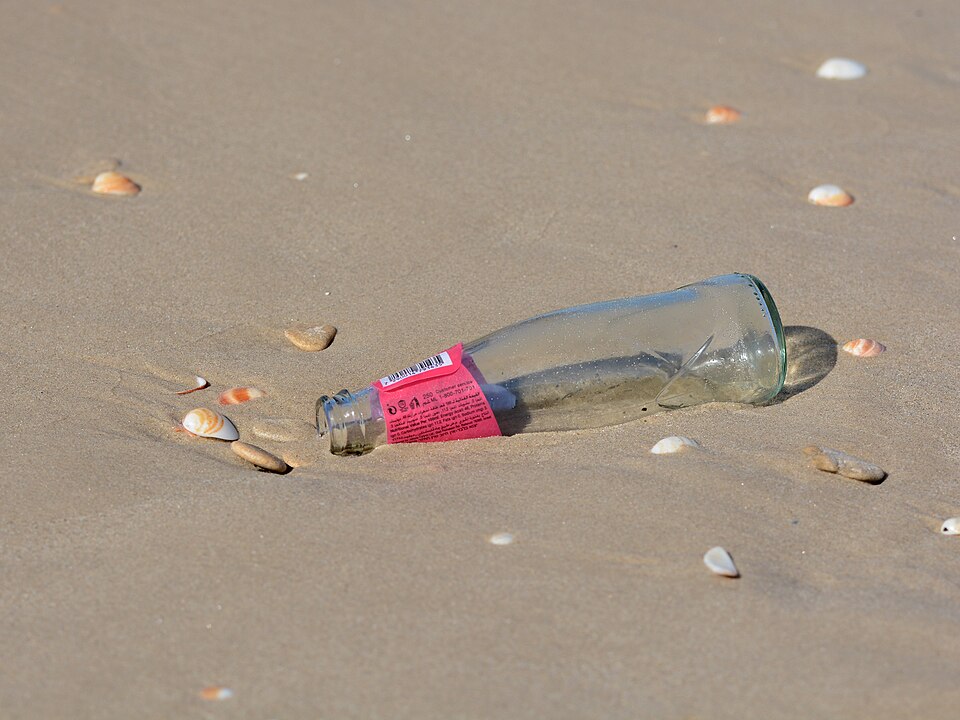 A glass bottle lying on a beach, the classic vessel for messages at sea - one such bottle drifted for 108 years before being recovered in 2015