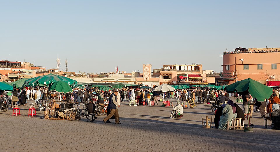 Crowds, market stalls and umbrellas filling Jemaa el-Fnaa square in Marrakech at dusk