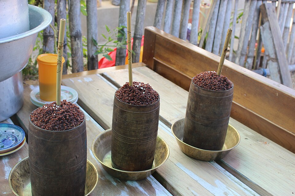 Tall bamboo container of tongba, the Nepalese fermented millet beer, served with a metal straw