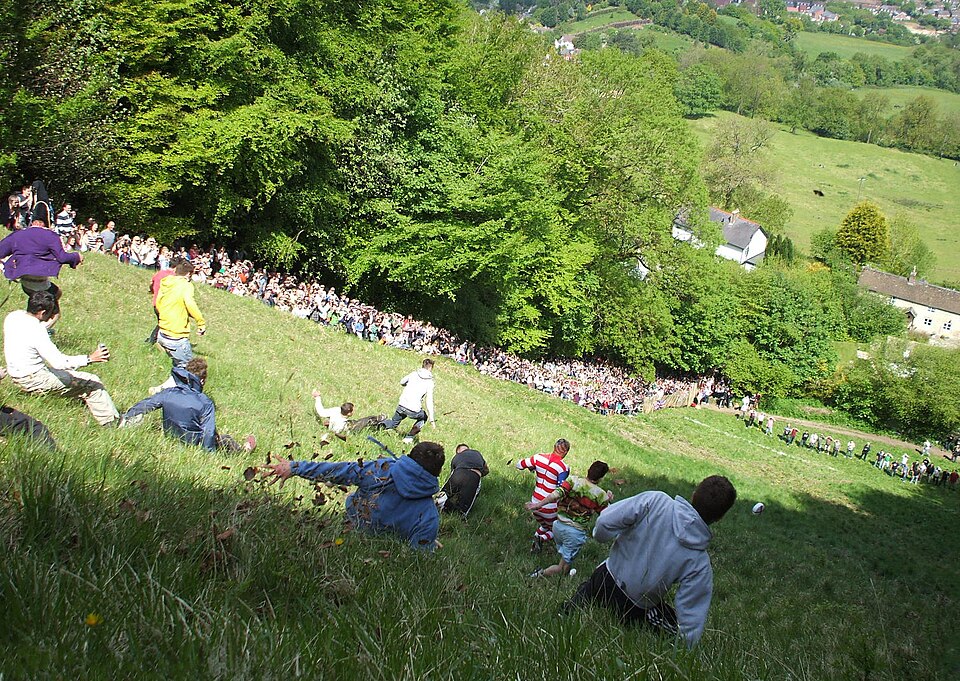 Competitors tumbling down the extremely steep Cooper Hill in Gloucestershire England during the annual cheese rolling race, watched by a crowd