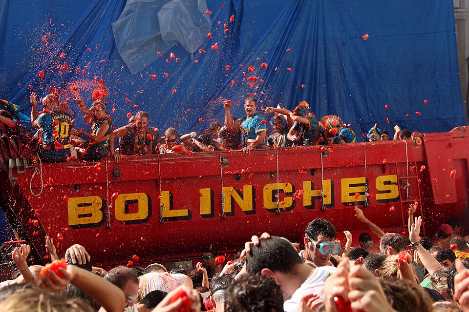 Thousands of participants drenched in tomato pulp throwing tomatoes during La Tomatina festival in Bunol, Valencia, Spain
