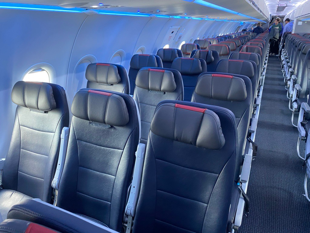 Modern aircraft economy cabin interior with seats arranged in rows - the cabin environment dulls taste buds by approximately thirty percent due to low pressure and humidity