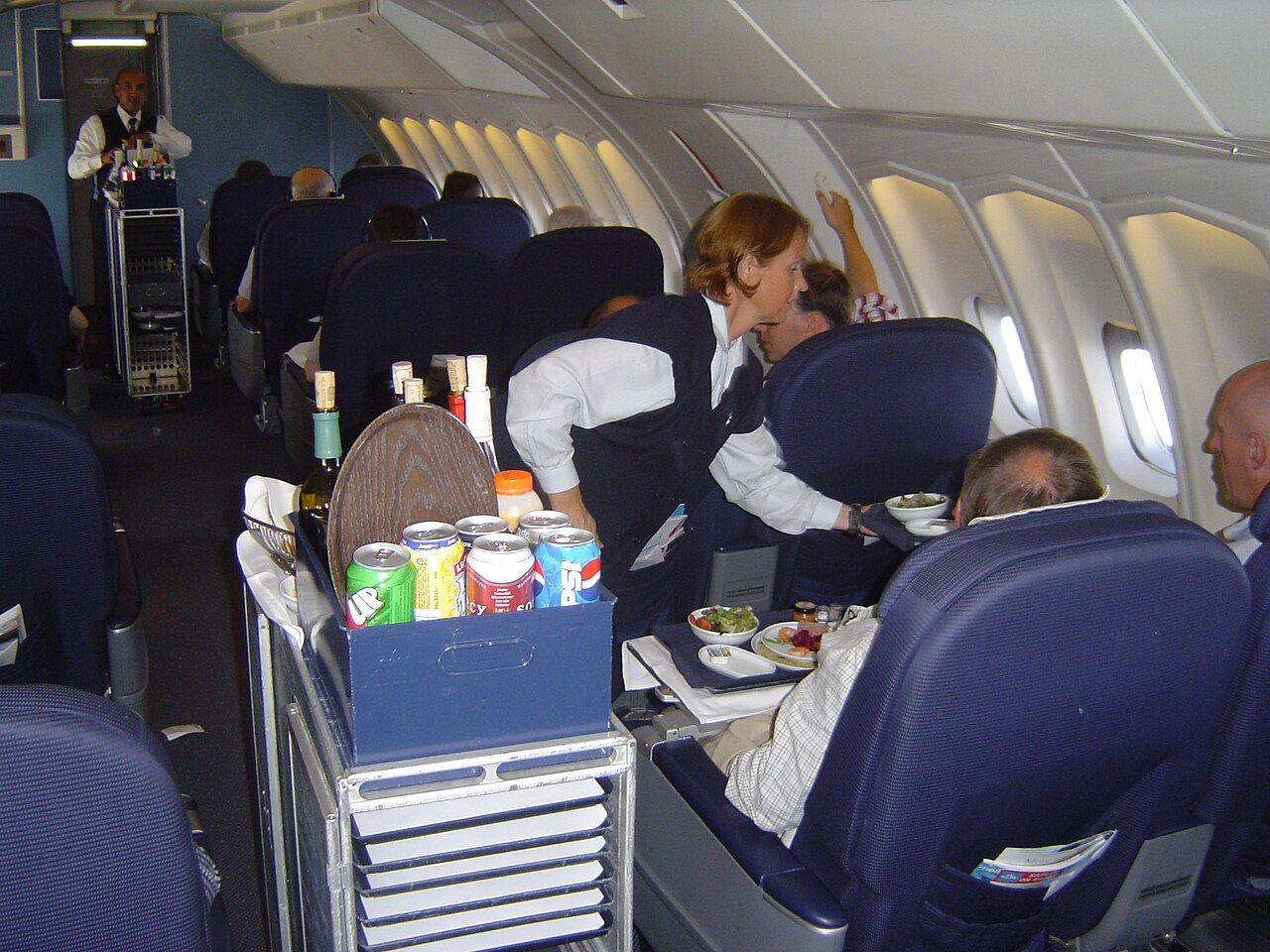Inflight meal trolley being wheeled down an aircraft aisle - airline meals are reheated from chilled or frozen state in galley ovens that produce inconsistent results